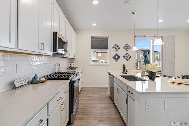 1953 Morgan Dr, Erie, CO 80516 - kitchen with appliances with stainless steel finishes, a sink, light wood-style flooring, backsplash, and light countertops