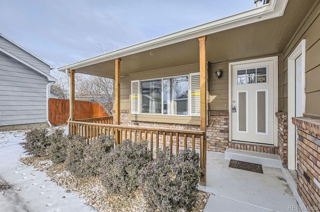 snow covered property entrance featuring a porch