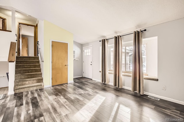 interior space featuring a textured ceiling, dark wood-type flooring, and lofted ceiling