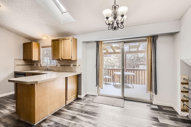 kitchen featuring kitchen peninsula, backsplash, decorative light fixtures, and an inviting chandelier