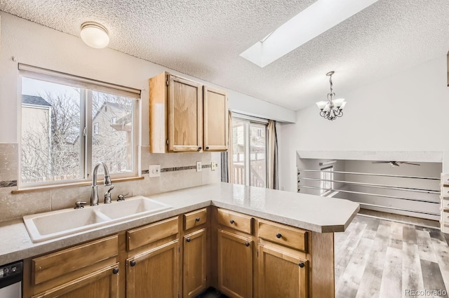 kitchen featuring kitchen peninsula, stainless steel dishwasher, a textured ceiling, sink, and pendant lighting