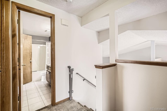 hall with light tile patterned floors and a textured ceiling