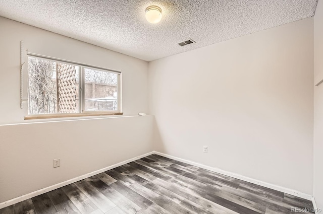 spare room featuring dark hardwood / wood-style flooring and a textured ceiling