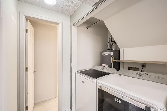 laundry area featuring washer and dryer, gas water heater, light tile patterned floors, and a textured ceiling