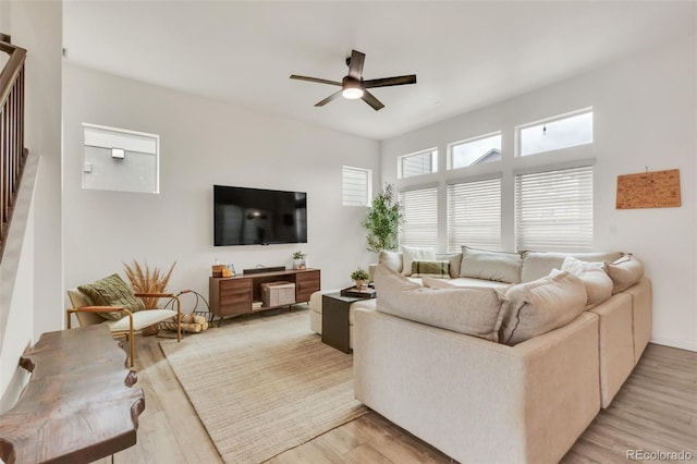 living room with light wood-style floors, stairs, and ceiling fan