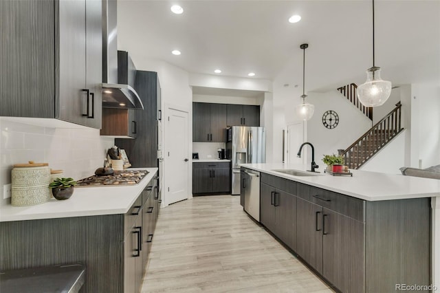 kitchen with a sink, light wood finished floors, light countertops, stainless steel appliances, and backsplash