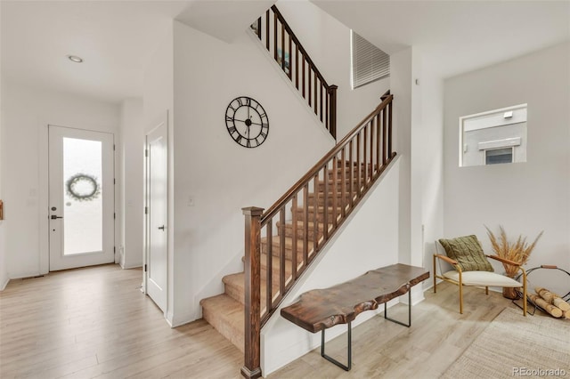 foyer featuring stairs, baseboards, and light wood finished floors