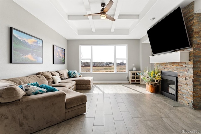 living room featuring coffered ceiling, beam ceiling, a fireplace, baseboards, and ceiling fan