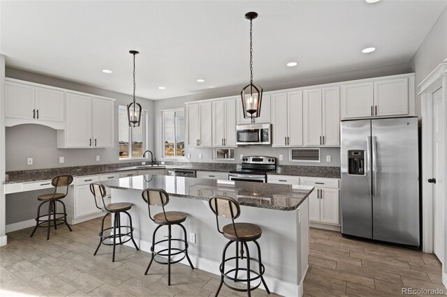 kitchen with white cabinets, stainless steel appliances, a sink, a breakfast bar area, and a center island