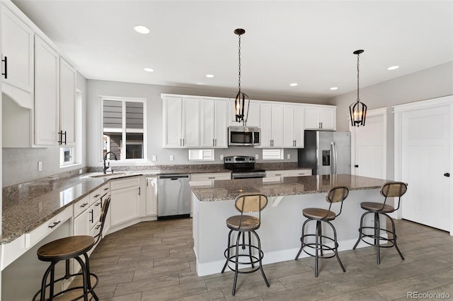 kitchen featuring a kitchen island, a sink, a breakfast bar area, and appliances with stainless steel finishes