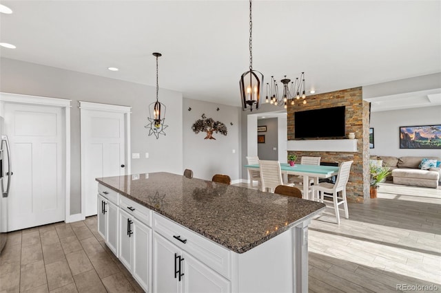 kitchen featuring a notable chandelier, white cabinetry, a center island, open floor plan, and light wood-type flooring