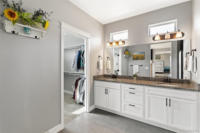 bathroom featuring double vanity, a walk in closet, tile patterned flooring, and a sink