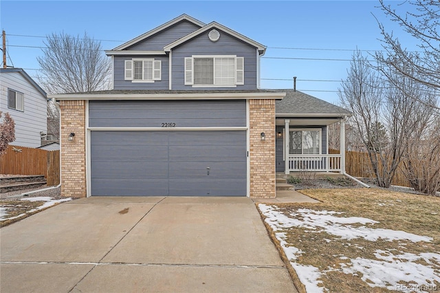 traditional-style house with brick siding, covered porch, concrete driveway, fence, and a garage