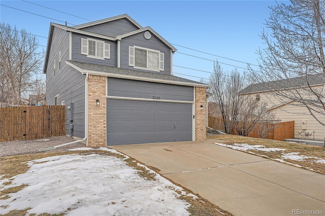 view of front of house featuring an attached garage, driveway, fence, and brick siding