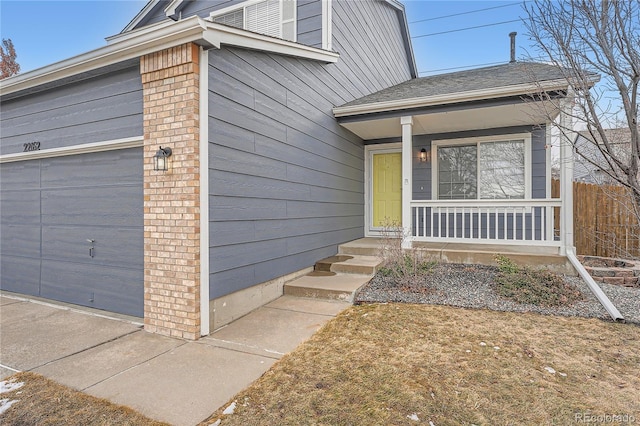 view of front of house with a porch, an attached garage, and brick siding