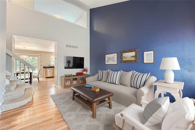 living area featuring baseboards, visible vents, an accent wall, wood finished floors, and stairs