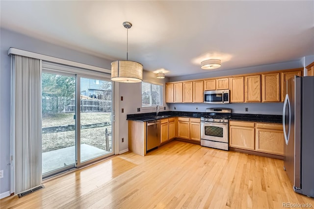 kitchen with visible vents, dark countertops, stainless steel appliances, light wood-type flooring, and a sink