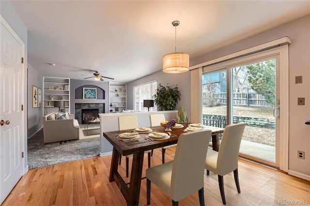 dining room featuring light wood finished floors, plenty of natural light, and a fireplace