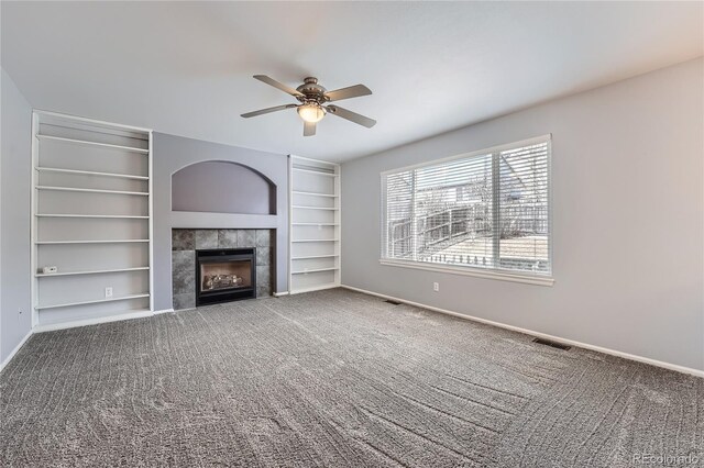 unfurnished living room featuring visible vents, baseboards, a ceiling fan, a tile fireplace, and carpet floors