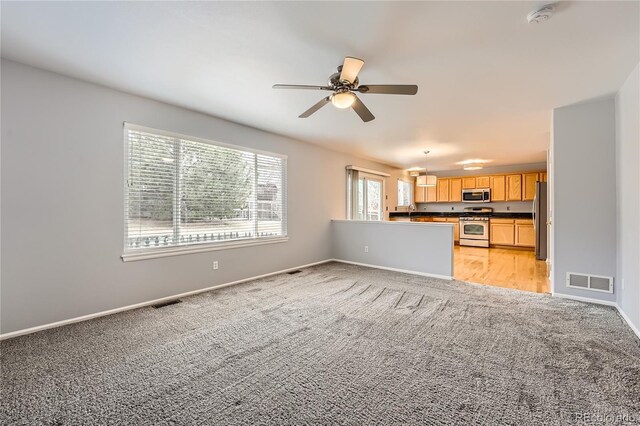 interior space featuring stainless steel appliances, dark countertops, light colored carpet, and baseboards