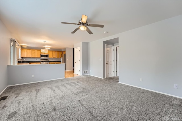 unfurnished living room featuring light carpet, visible vents, baseboards, and a ceiling fan