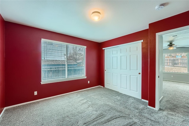 unfurnished bedroom featuring carpet floors, a closet, multiple windows, and baseboards