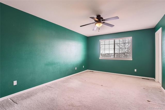 carpeted spare room featuring ceiling fan, visible vents, and baseboards