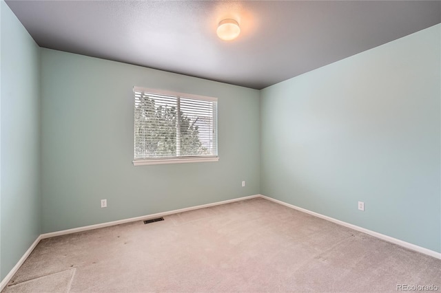 unfurnished room with carpet, visible vents, and baseboards