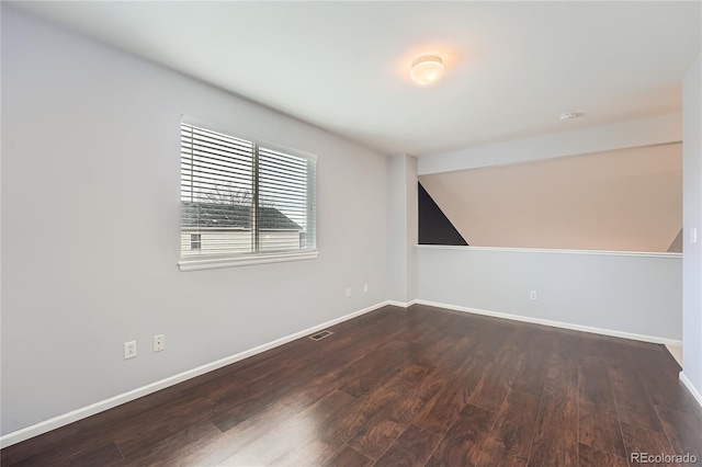 spare room with lofted ceiling, visible vents, baseboards, and wood finished floors