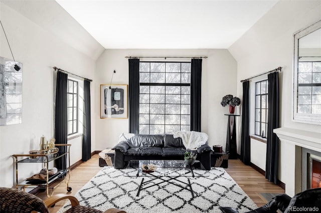 living area featuring light wood-style floors, baseboards, and vaulted ceiling