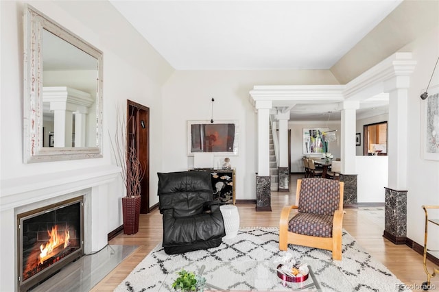 living area with decorative columns, lofted ceiling, and wood finished floors
