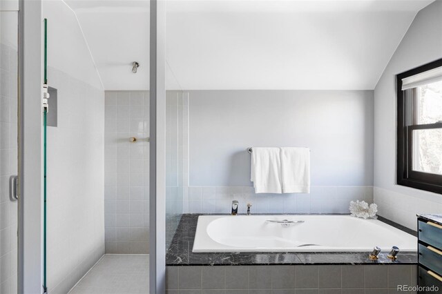 full bath featuring a tile shower, a bath, vanity, and vaulted ceiling