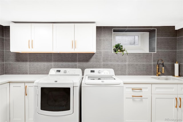 laundry area featuring washer and dryer, tile walls, a sink, and cabinet space