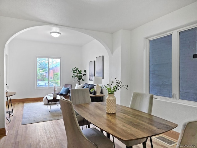 160 W Bayaud Ave, Denver, CO 80223 - dining space featuring arched walkways, light wood finished floors, and baseboards