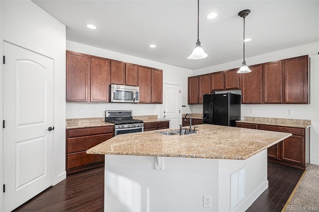 kitchen featuring dark wood-type flooring, sink, an island with sink, decorative light fixtures, and stainless steel appliances