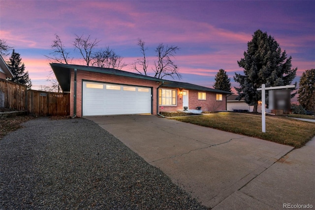 ranch-style home featuring a garage and a lawn