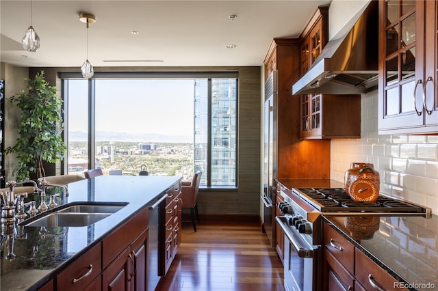 kitchen featuring backsplash, appliances with stainless steel finishes, dark hardwood / wood-style flooring, pendant lighting, and wall chimney exhaust hood