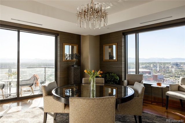 dining space featuring wood walls, hardwood / wood-style flooring, a mountain view, and an inviting chandelier