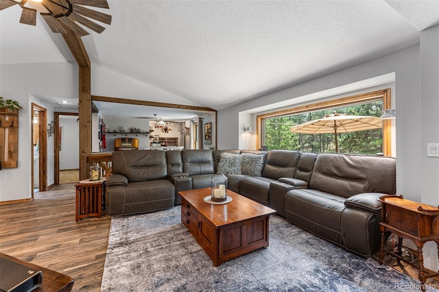 living room with hardwood / wood-style flooring, ceiling fan, lofted ceiling, and a textured ceiling