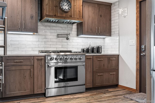 kitchen with custom range hood, dark wood-type flooring, high end range, and decorative backsplash