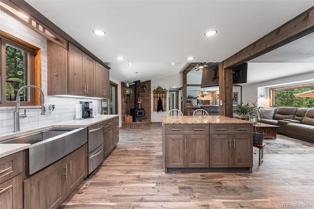 kitchen featuring light wood-type flooring, sink, light stone counters, and vaulted ceiling with beams