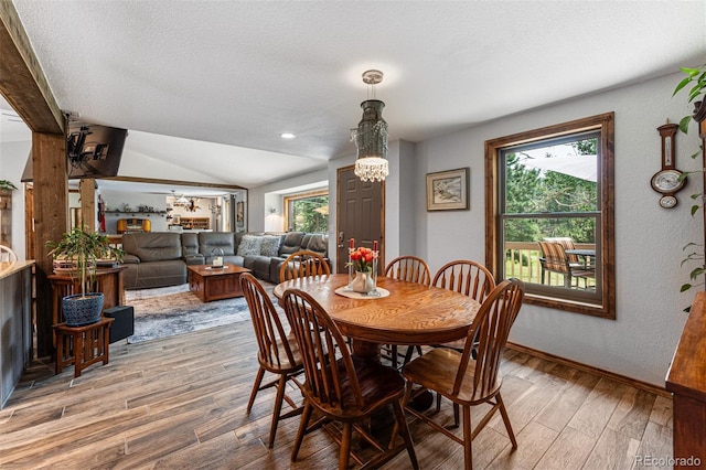 dining room with vaulted ceiling, hardwood / wood-style floors, and a textured ceiling