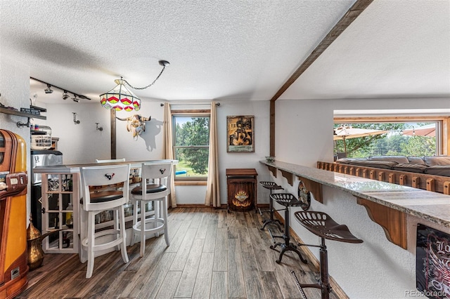 dining room featuring dark wood-type flooring, rail lighting, and a textured ceiling