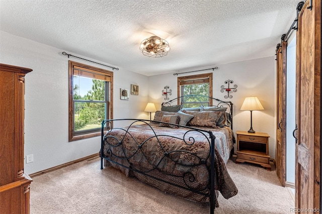 bedroom featuring a barn door, light carpet, and a textured ceiling