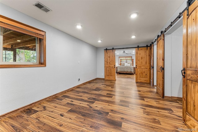 unfurnished room with a barn door and hardwood / wood-style floors