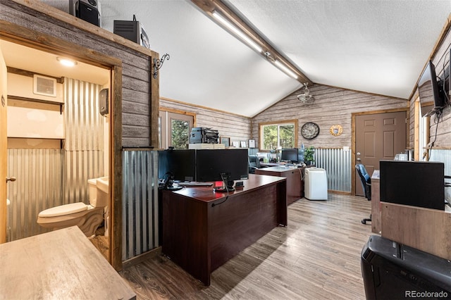 office area featuring lofted ceiling with beams, wood-type flooring, wooden walls, and a textured ceiling