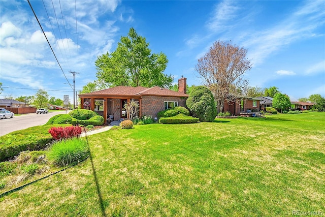 ranch-style home featuring a chimney, a front yard, and brick siding