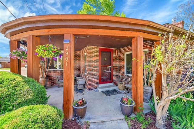 entrance to property featuring brick siding and a chimney
