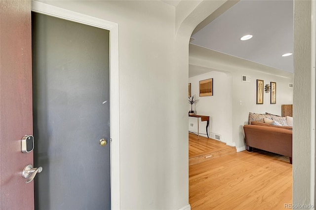 corridor featuring arched walkways, wood finished floors, recessed lighting, and baseboards