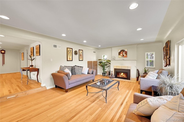 living area with light wood finished floors, recessed lighting, a fireplace with flush hearth, and baseboards